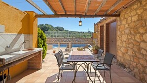 Une terrasse avec une table et des chaises, un évier et une vue sur une piscine.