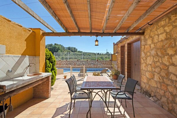 A patio with a table and chairs, a sink, and a view of a swimming pool.