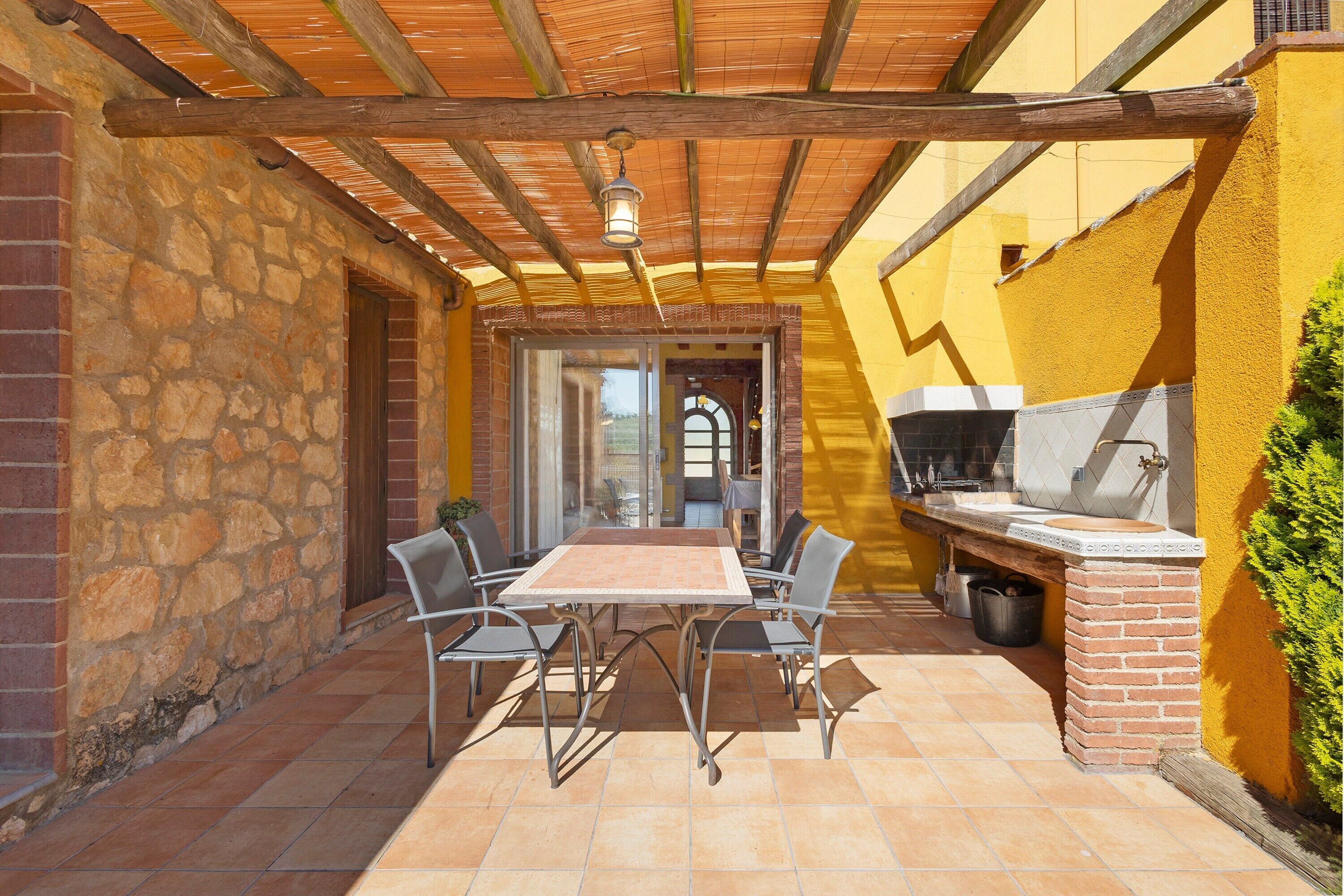 Een terras met een tafel, stoelen, een barbecue en een stenen muur.