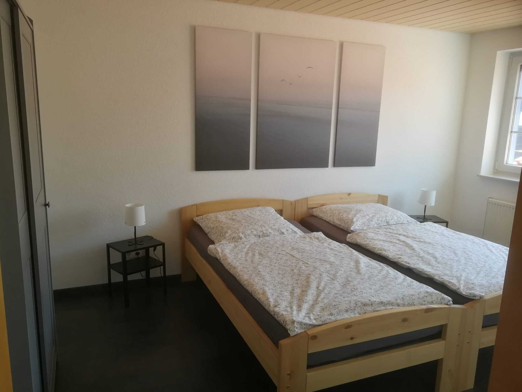 A room with a bed, a nightstand, a lamp, and a window.