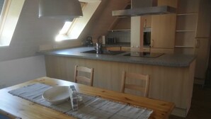 A kitchen with a wooden table, chairs, a countertop, and a skylight.