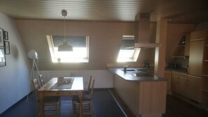 A compact kitchen with a dining area, wooden cabinets, and a small island.
