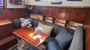 Un intérieur de camping-car compact comprenant un coin repas, un canapé et une fenêtre avec des rideaux.