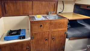 Une petite cuisine équipée avec une cuisinière, un évier et des placards en bois.