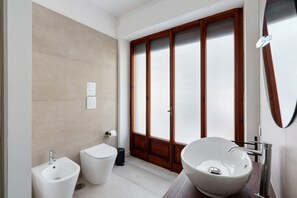 Un bagno moderno con bidet, servizi igienici e un ampio lavandino.