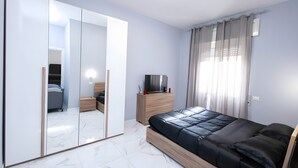 Una camera da letto con un letto, una TV, un armadio e uno specchio.