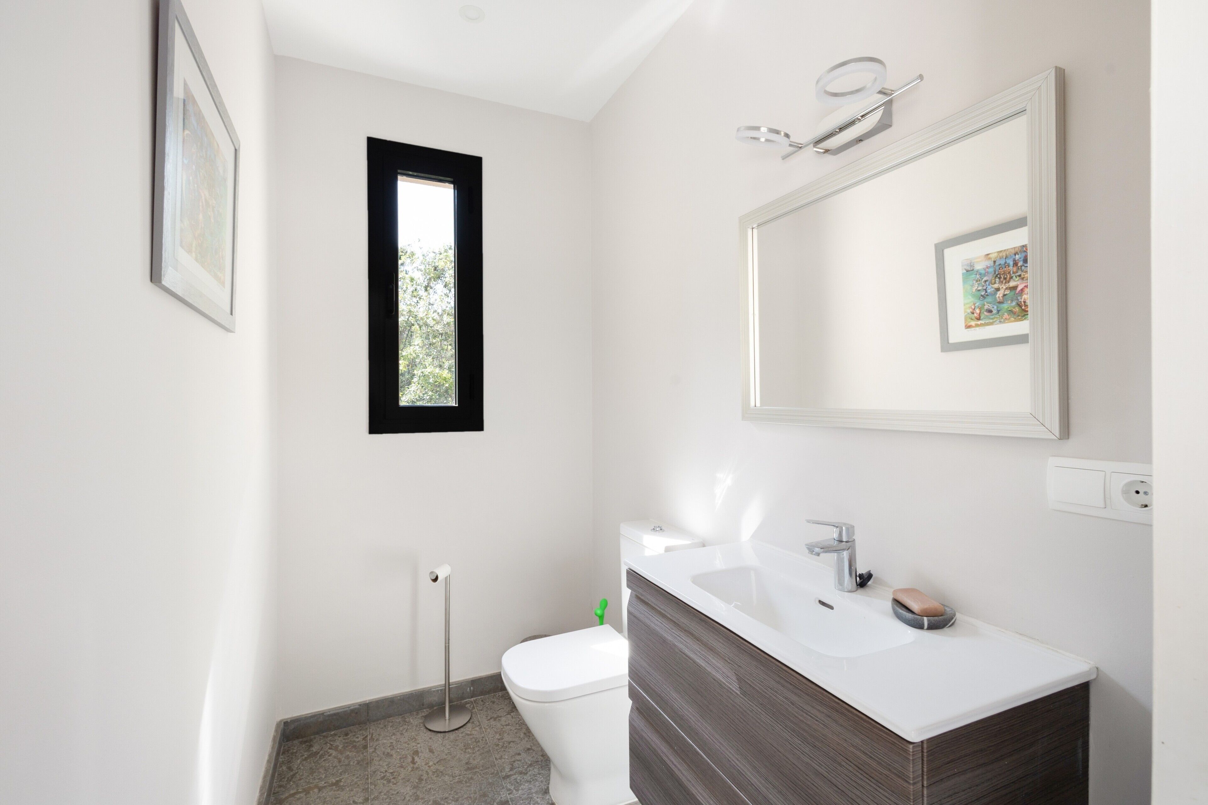 A modern bathroom with a toilet, sink, and mirror.