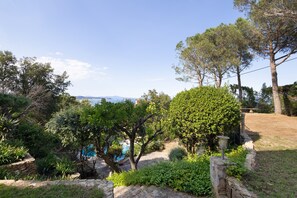 A garden with a pool, stone walls, and trees. - Holiday Home 'Sa Punta 11' with Sea View, Private Pool and Wi-Fi (Sa Riera)