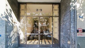 L'ingresso di un edificio con una porta in vetro, una scalinata che vi conduce e un cartello sopra la porta.