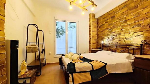 Una stanza con un letto, una parete in legno, una finestra e una lampada a sospensione.