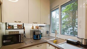 Una cucina con forno a microonde, macchina del caffè e una finestra vista alberi.