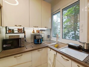 Eine Küche mit Mikrowelle, Kaffeemaschine und einem Fenster mit Blick auf Bäume.