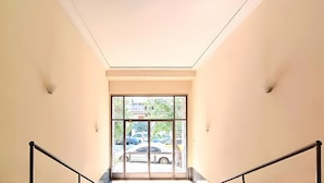 Una scala con ringhiere in metallo che conduce a una porta in vetro con vista su auto parcheggiate all'esterno.