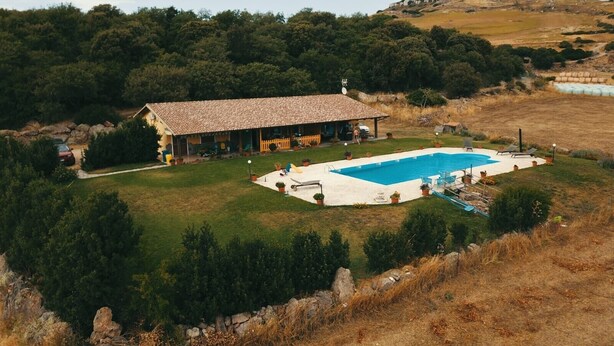 A house with a swimming pool, surrounded by a grassy area and trees. - Holiday Home 'Farm Holiday Sa Raighina - Right' with Shared Pool, Wi-Fi and Air Conditioning (Nulvi)