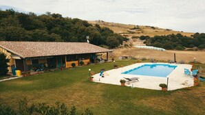 A house with a swimming pool, surrounded by a grassy lawn and trees. - Holiday Home 'Farm Holiday Sa Raighina - Right' with Shared Pool, Wi-Fi and Air Conditioning (Nulvi)