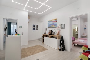 Ein modernes Hotelzimmer mit Bett, Schreibtisch, Kaffeemaschine und einem Gemälde an der Wand.