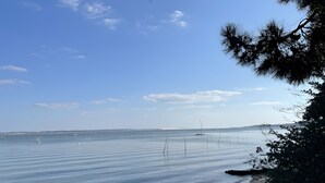 Une mer calme sous un ciel dégagé, une côte lointaine et une jetée qui s’avance dans l’eau.