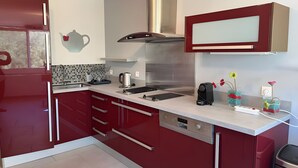 Une cuisine moderne avec des meubles de rangement rouges, des appareils en acier inoxydable et un four à micro-ondes.