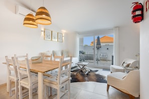 A dining area with a wooden table and chairs, a small side table, and a glass partition.
