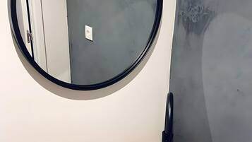 Een badkamer met een ronde spiegel, een stenen wastafel en een kleine zeepfles.