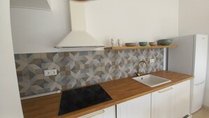 A kitchen with a geometric backsplash, a black induction cooktop, a white sink, and a built-in oven. - Casa Lusitano With Jacuzzi by Valada Village (Valada)