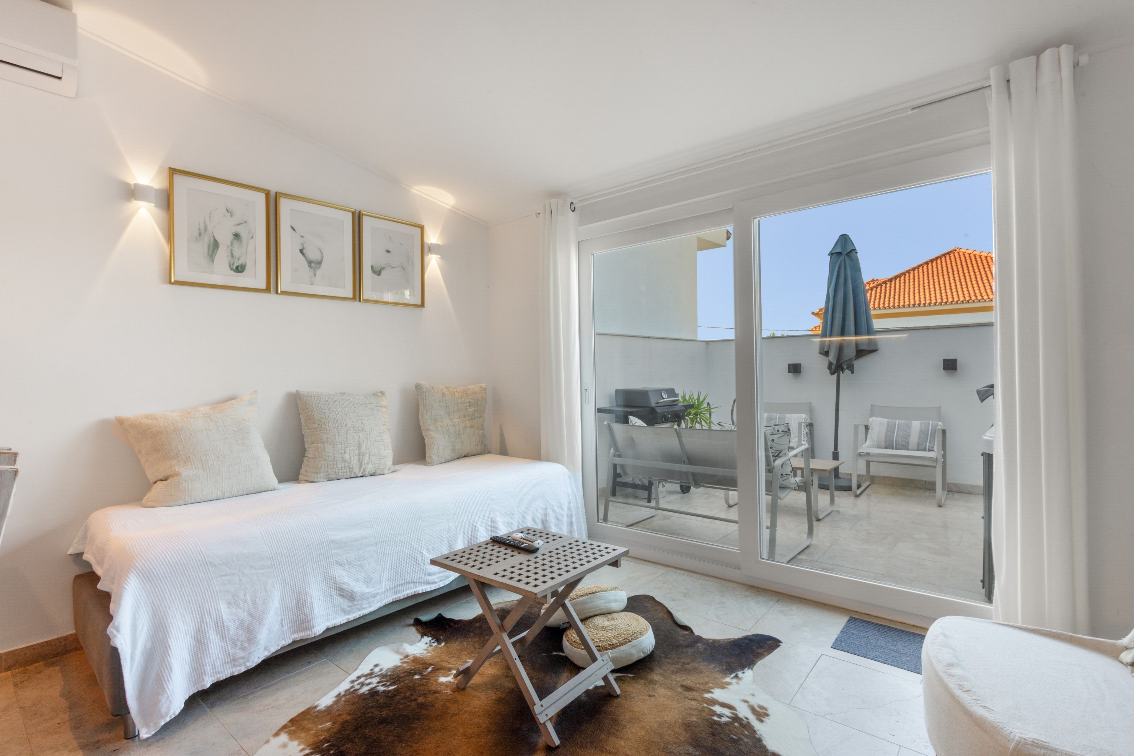 A bedroom with a bed, a small table, and a cowhide rug.