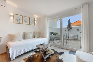 A bedroom with a bed, a small table, and a cowhide rug.