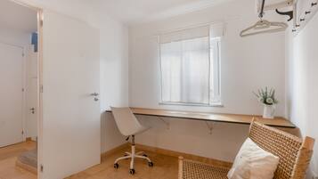 Une pièce avec un bureau, une chaise, une fenêtre, une porte et une petite plante.