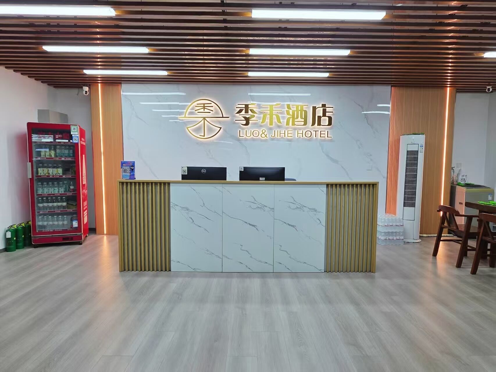 A hotel reception desk with a marble top, a red vending machine, and a large air conditioning unit.