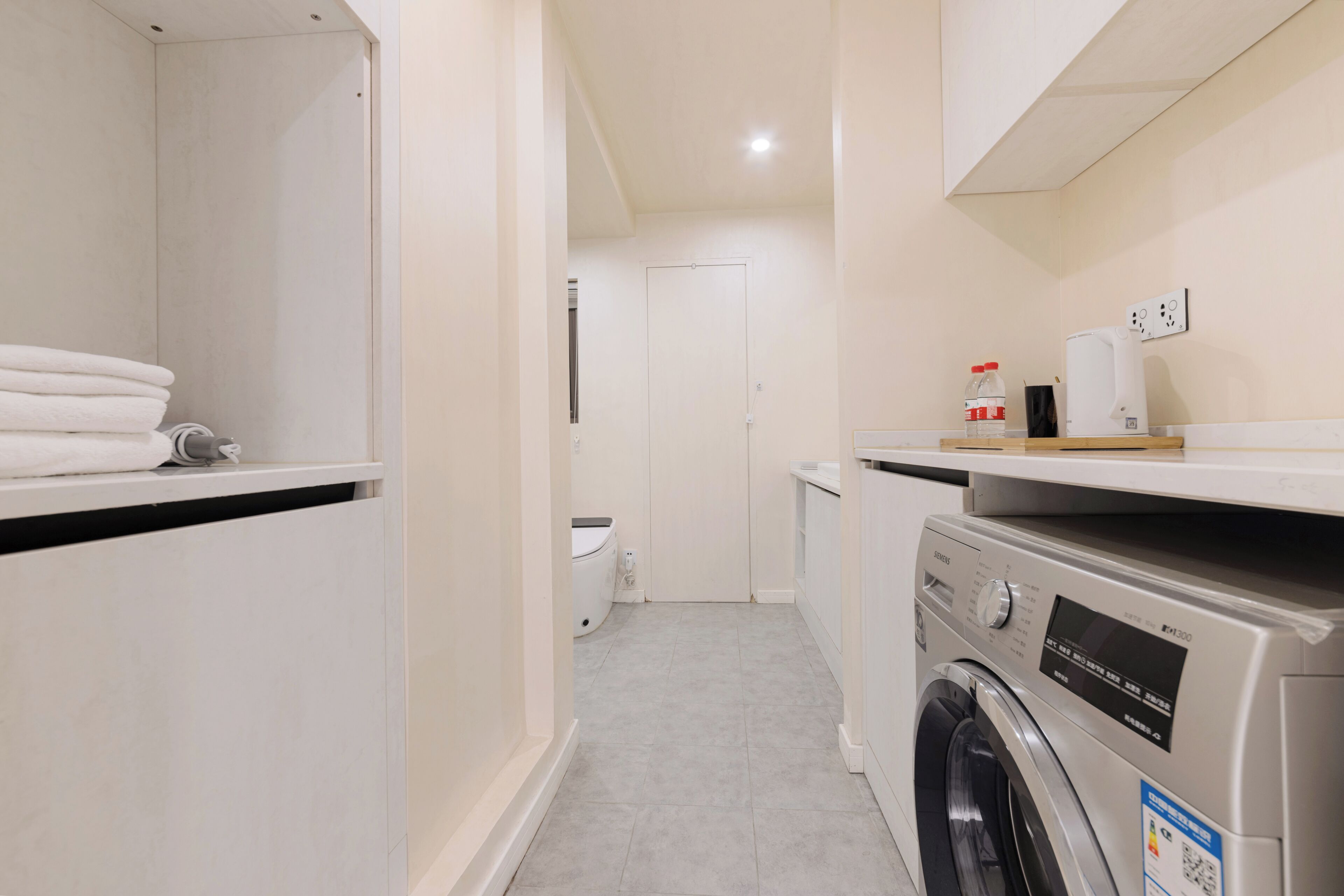Un espace buanderie comprenant un lave-linge, un sèche-linge et des piles de serviettes.
