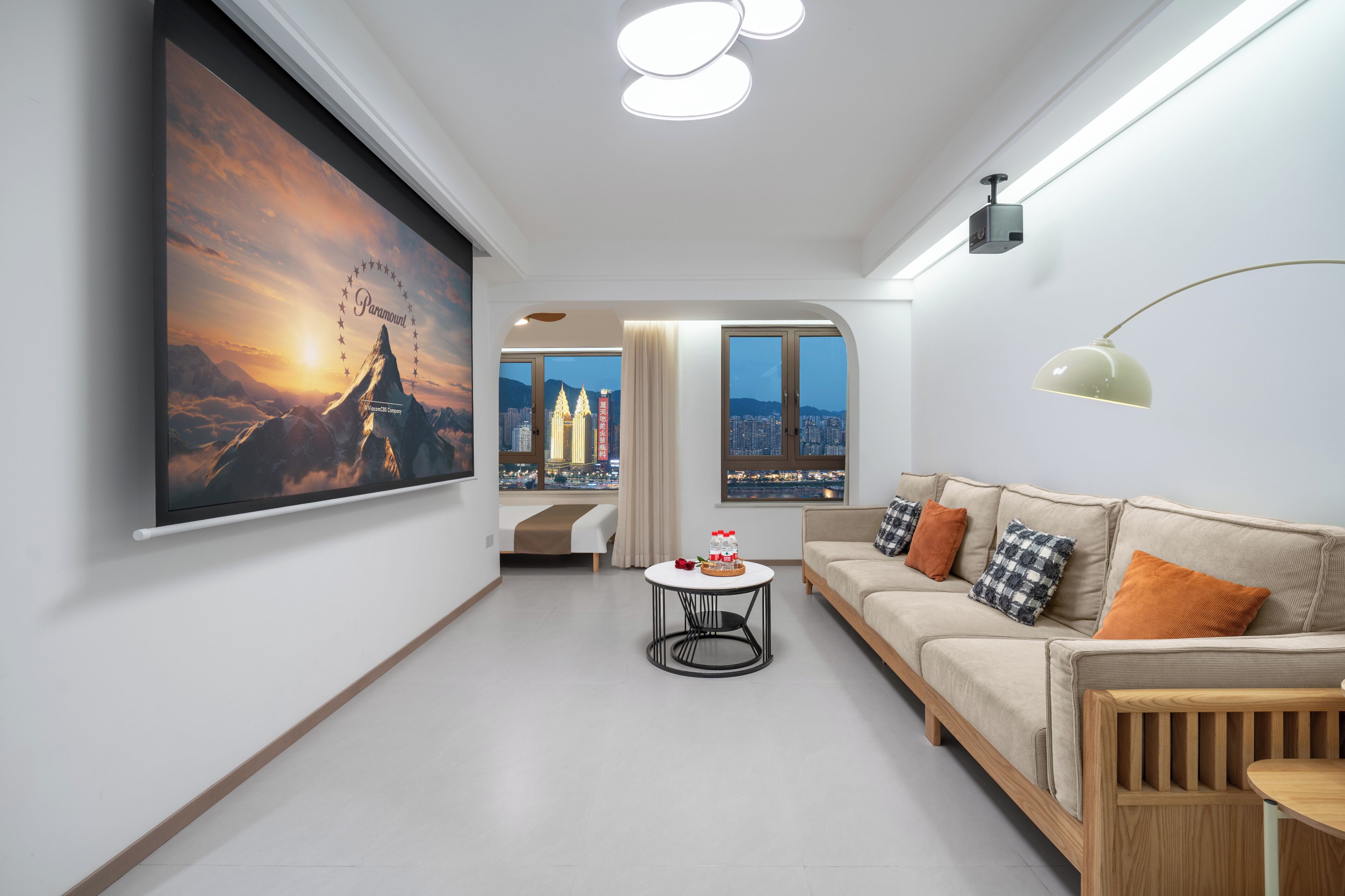 Ein modernes Wohnzimmer mit einer Couch, einem Couchtisch und einem großen Gemälde von einer Berglandschaft.