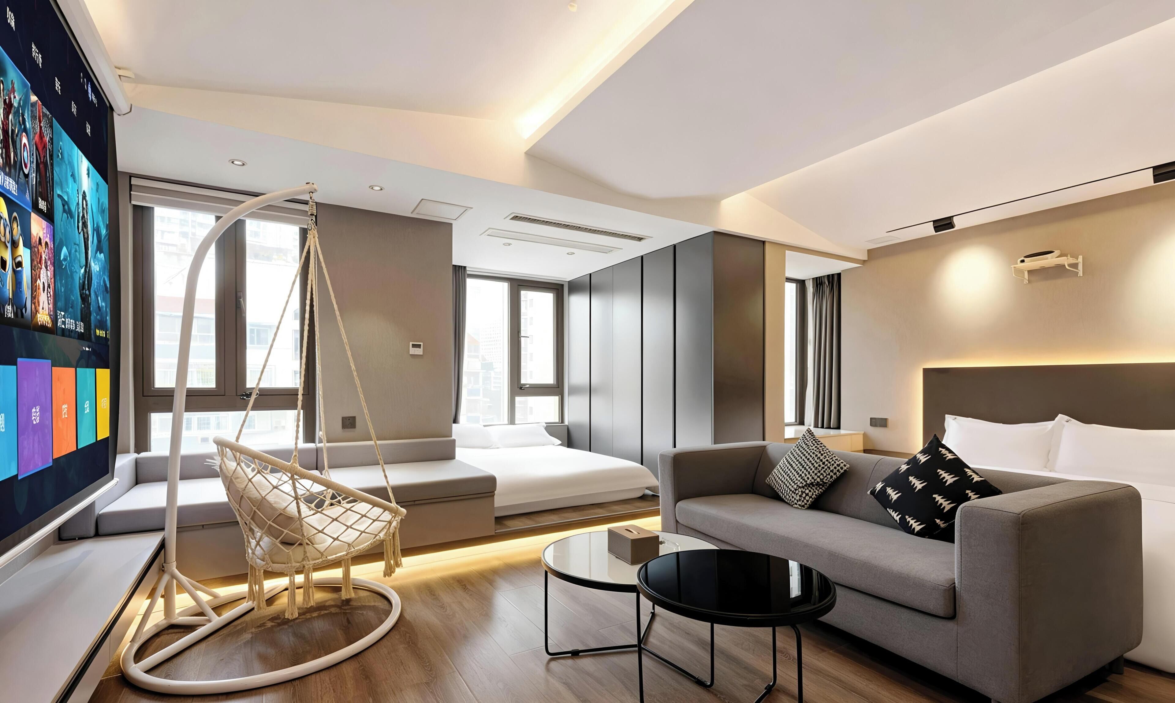 Habitació d'hotel moderna amb sofà, cadira penjant, llit, televisió i una finestra gran.