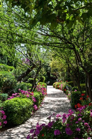 Ein von üppigem Grün und farbenprächtigen Blumen gesäumter Weg, der durch einen Garten führt.