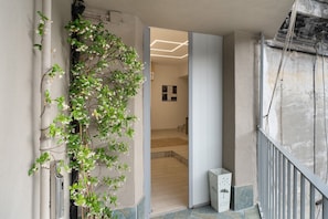 A hallway with a plant, a door leading to a room, and a staircase. - Le Stanze In Centro - Deluxe Double Room (Naples)