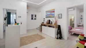 A modern hotel room with a bed, a desk, a coffee machine, and a painting on the wall. - Le Stanze In Centro - Deluxe Double Room (Naples)