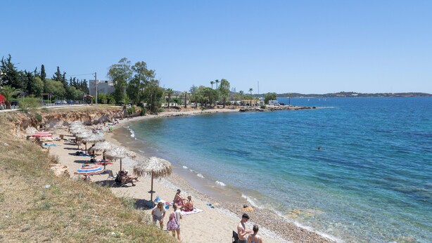 A beach with umbrellas, people, and a clear blue sea. - Studio Apartment 'Athens-riviera in Front' with Sea View, Wi-Fi and Air Conditioning (Voula)