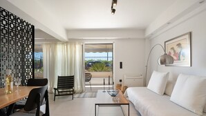 A modern room with a sofa, dining table, chairs, a coffee table, a decorative screen, and a view through a glass door. - Studio Apartment 'Athens-riviera in Front' with Sea View, Wi-Fi and Air Conditioning (Voula)