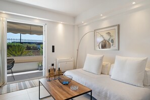 A modern bedroom with a bed, bedside table, lamp, and a view of greenery through a sliding door. - Studio Apartment 'Athens-riviera in Front' with Sea View, Wi-Fi and Air Conditioning (Voula)