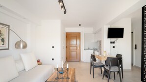 A modern living room with a sofa, a coffee table, and a dining area with chairs and a table. - Studio Apartment 'Athens-riviera in Front' with Sea View, Wi-Fi and Air Conditioning (Voula)