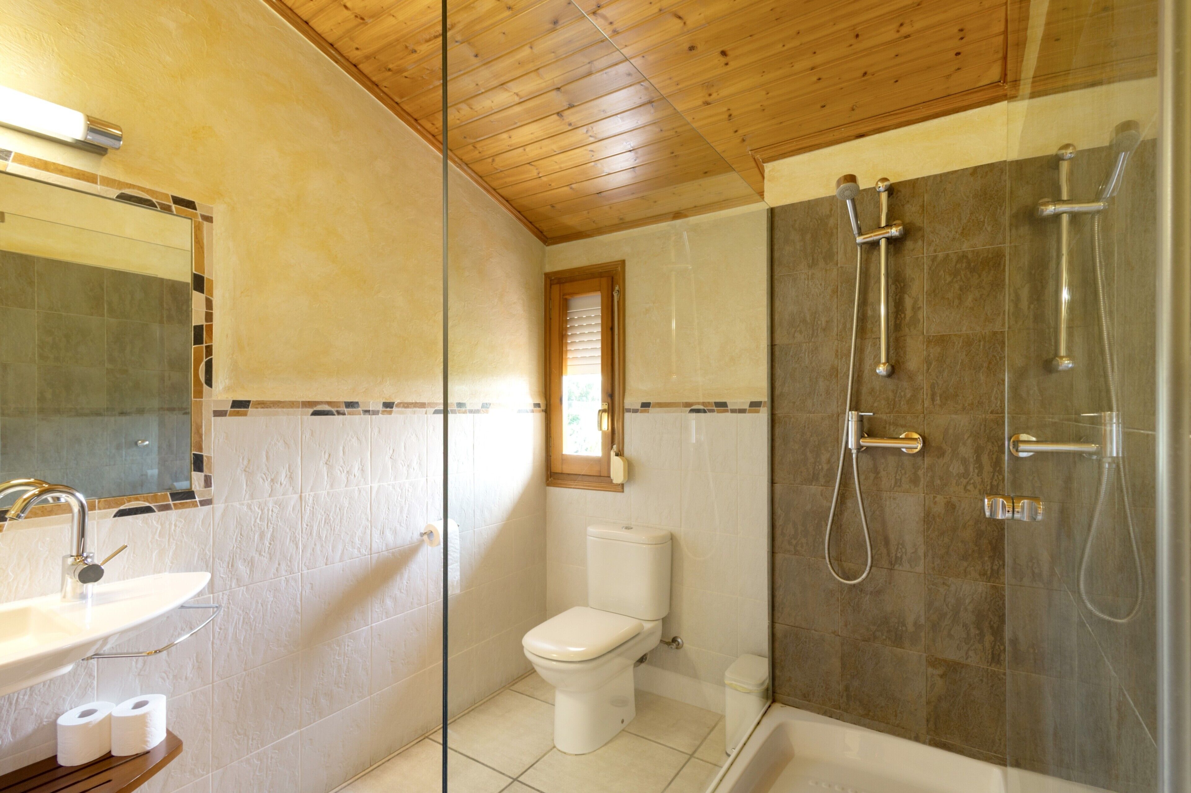 Un baño con inodoro, lavamanos y zona de ducha.