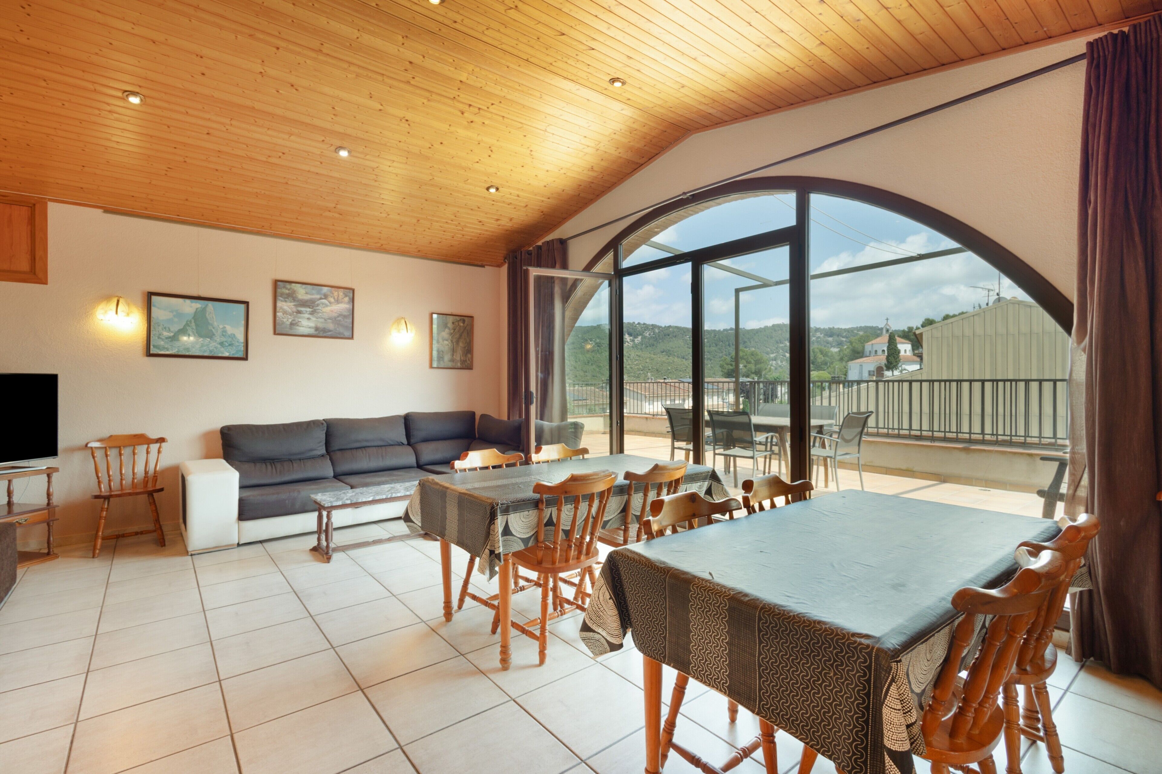 Un'ampia zona giorno con un grande tavolo da pranzo, sedie in legno, un divano e una televisione.