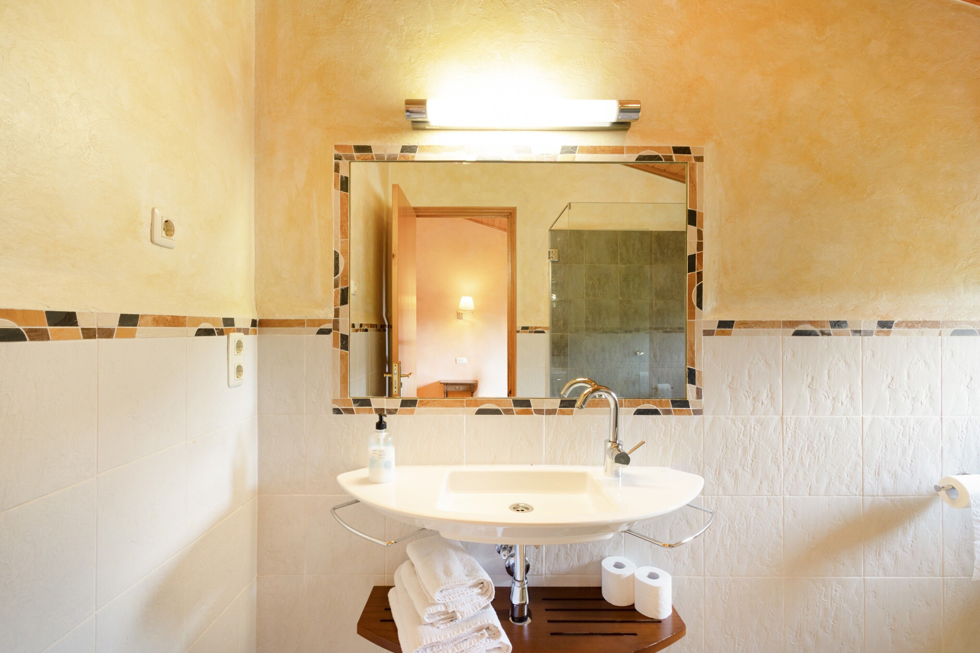 Une salle de bain avec un lavabo, un miroir et du papier toilette.
