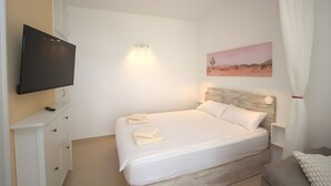 A bedroom with a bed, a TV, a bedside table, a nightstand, and a painting on the wall. - Playa del Sol – Sea View Studio in Puerto Rico (Mogán)