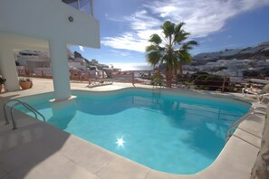 A swimming pool with a view of a coastal town and palm trees. - Playa del Sol – Sea View Studio in Puerto Rico (Mogán)
