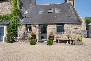 A stone house with a sloped roof, a small porch, and a door leading to the interior. - Maisonette Ti Arzou – 300m from the Beach (Le Conquet)