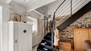 A room with a staircase, a mannequin, a wooden cabinet, and a white wardrobe. - Maisonette Ti Arzou – 300m from the Beach (Le Conquet)