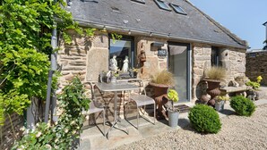 A stone building with a tiled roof, outdoor seating, and potted plants. - Maisonette Ti Arzou – 300m from the Beach (Le Conquet)