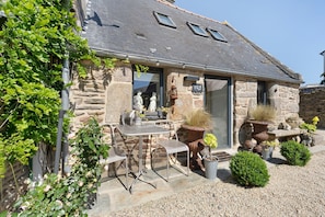 A stone building with a tiled roof, outdoor seating, and potted plants. - Maisonette Ti Arzou – 300m from the Beach (Le Conquet)