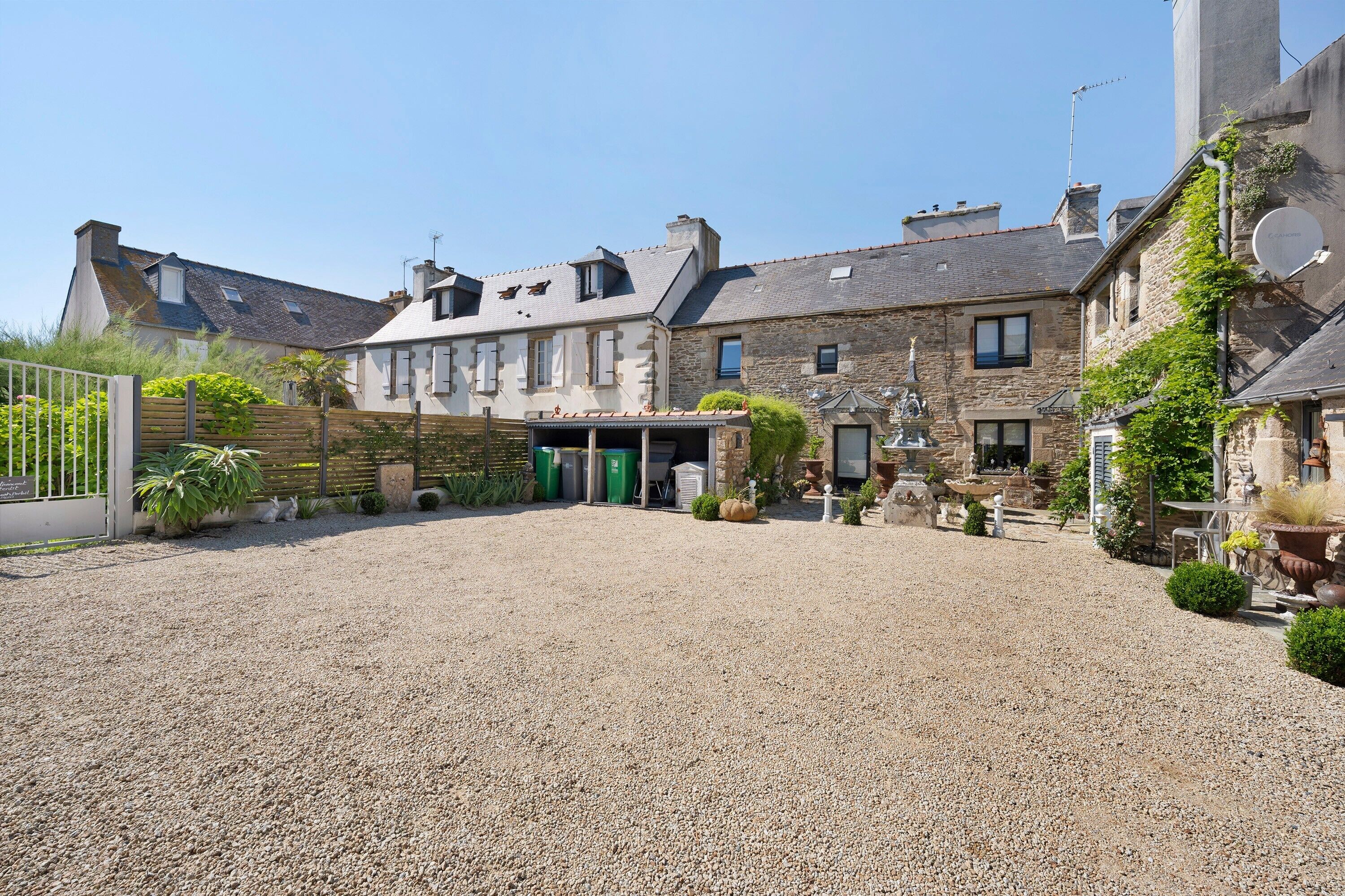 A courtyard with a gravel ground, stone buildings, and a green door.