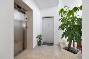 A hallway with an elevator, a door, and a potted plant. - Apartment 'Etesia' with Balcony, Wi-Fi and Air Conditioning (Santa Flavia)